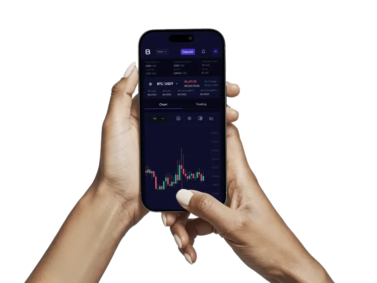 A phone held in one hand, showing the BTC/USDT price with its daily figures above a candlestick chart.